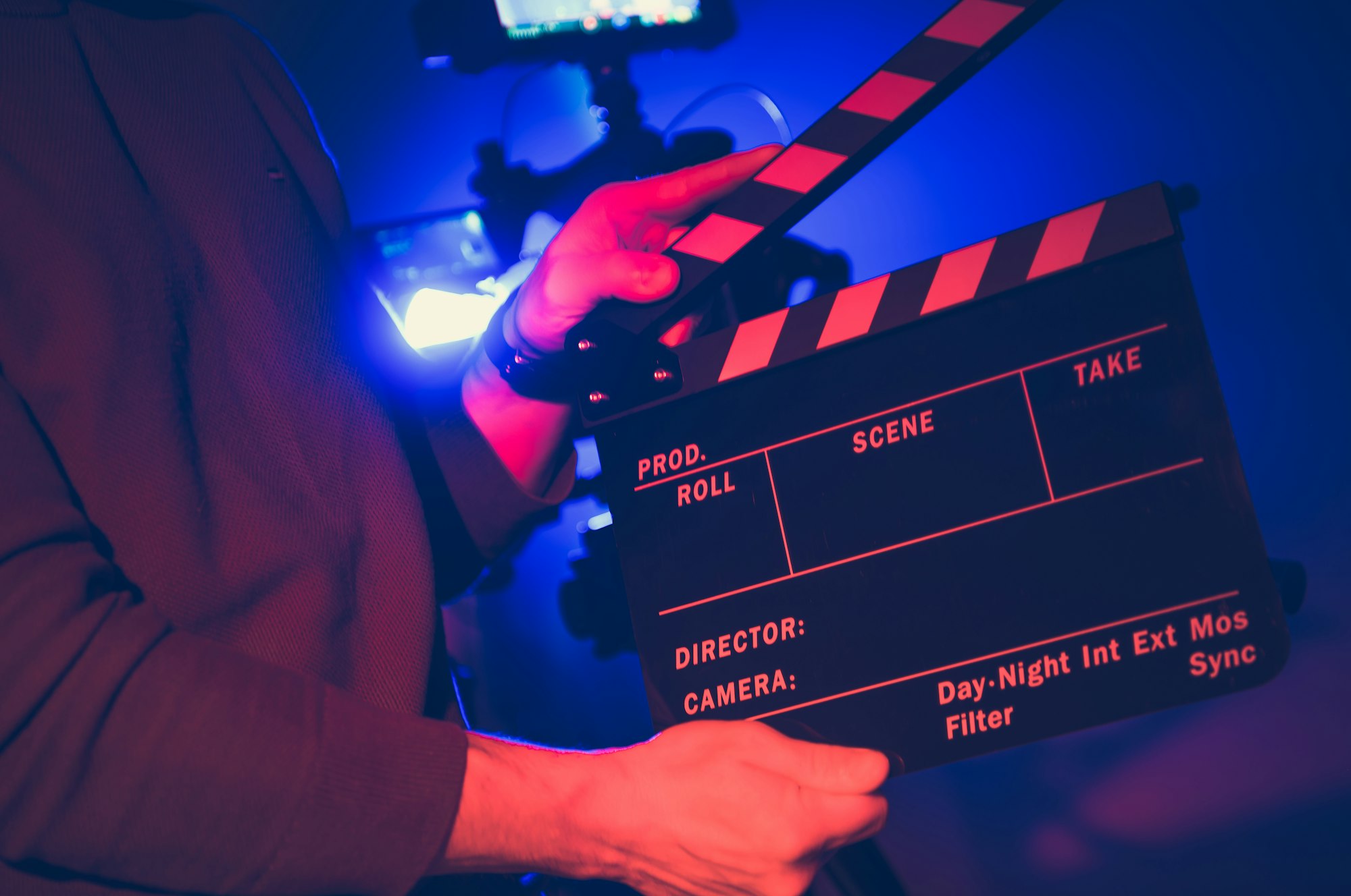 A Filmmaker Prepares a Clapperboard for a Nighttime Shoot Indoors With Colorful Lighting Effects